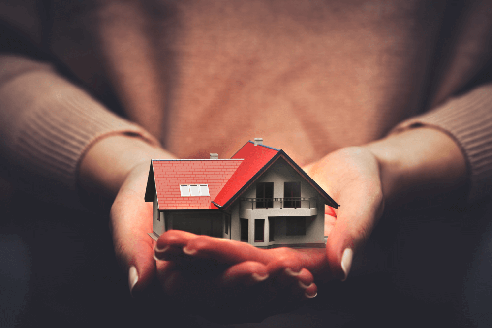 Hands cradling a small house, representing eligible loan collateral